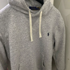 Grå hoodie från Polo Ralph Lauren - Jag säljer denna fina tröjan som jag har använt få gånger det är inga skador eller liknande på tröjan asså ser ut o vara ny priset går att diskutera vid snabb affär