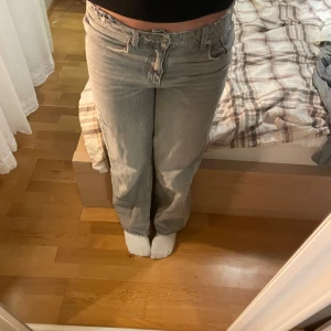 Grå jeans med slitningar - Säljer ett par grå jeans med en avslappnad passform och slitningar på framsidan. De har en klassisk femficksdesign. De är egentligen högmidhade men ser mer ut som mid-waist. Storlek 152, men passar mig i längden som ör 162. 