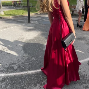 Vinröd balklänning  - Elegant vinröd långklänning i satin. Köpt på brudspeciallisten. Klänningen har ett litet släp och en slit på framsida. Den har inbyggd bh. Har endast använt klänningen vid ett tillfälle och passar perfekt till studentbal. Säljer eftersom jag är på jakt efter en annan. Pris kan diskuteras och köparen står för frakten ❤️