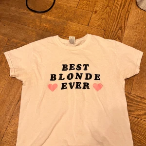 Vit t-shirt med tryck - Vit t-shirt med texten 'BEST BLONDE EVER' i svart och två rosa hjärtan. Kortärmad och rund halsringning, perfekt för en avslappnad stil.