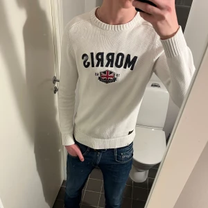 Morris tröja  - Säljer en stilren vit tröja från Morris med broderad logga och Union Jack-detalj på bröstet. Tröjan har långa ärmar och ribbade muddar vid ärmslut och nederkant. Jag är ca 183 och tröjan har blivit för liten. Passar dig bra som är allt mellan 170-180. Hör av dig vid frågor. 