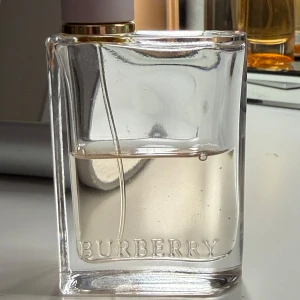 Burberry Her Eau de Parfum 50 ml - Elegant och tidlös parfym från Burberry i en stilren glasflaska med guld- och vitfärgad kork. Flaskan rymmer 50ml och det är cirka 28ml kvar och har en klassisk rektangulär form med Burberrys logotyp ingraverad.