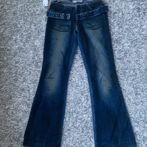 Lågmidjade jeans - Coola lågmidjade jeans utan fickor med en snygg skärp detalj runt. Finns bild på men lite försmå på modellen. Midjemått: ca 35 cm, ytterbenslängden ca 97 cm.☺️bootcut