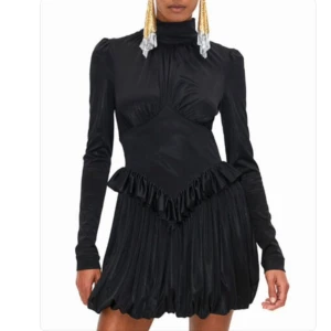 Klänning från Rabanne x H&M - Svart klänning i glansigt material. Tight runt midjan med en volang och puffig kjol. Tighta ärmar. Blixtlås bak. 