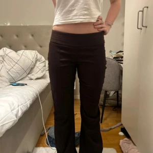 Kostymbyxor  - Snygga bruna byxor med låg midja och utsvängda ben. Perfekta för en trendig look. Byxorna har en bred resår i midjan för extra komfort.