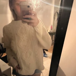 Vit stickad tröja med flätmönster - Mysig vit stickad tröja med ett klassiskt flätmönster. Perfekt för kyliga dagar med sin varma och bekväma design. Tröjan har långa ärmar och en rund halsringning. Passar s och m!