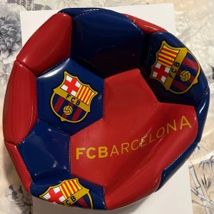 FC Barcelona fotboll - Snygg fotboll i FC Barcelonas klassiska färger röd och blå med klubbens emblem tryckt på flera paneler. Perfekt för fans som vill visa sitt stöd på planen eller i samlingen.