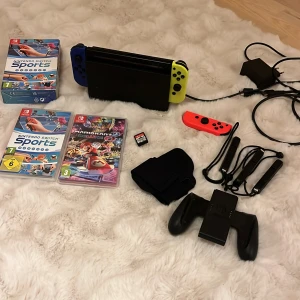 Nintendo Switch med spel och tillbehör - Säljer en Nintendo Switch med blå och gul Joy-Con, laddare och handkontroll. Inkluderar spelen Nintendo Switch Sports, Mario Kart 8 Deluxe och Super Mario Party. Perfekt för spelkvällar med vänner eller familj! 