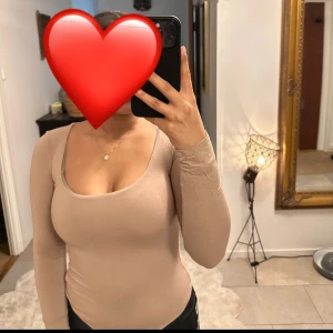 Beige långärmad bodysuit från Fashion Nova - Säljer en beige långärmad bodysuit från Fashion Nova. Den har en rundad halsringning och är tillverkad i ett mjukt och stretchigt material. 