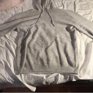 Merinoull hoodie - Säljer en stilren grå merinoull hoodie med långa ärmar och ribbade muddar. Perfekt för en avslappnad look. Tröjan är väldigt varm och skön.