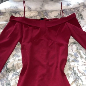 Vinröd klänning från NLY Trend - Elegant vinröd klänning från NLY Trend med offshoulder-design och smala axelband. Klänningen har en dragkedja i ryggen. Aldrig använt då den är för stor💕