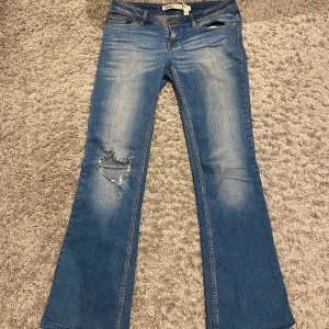 Blå bootcut jeans från Only - Säljer ett par blå lågmidjade bootcut jeans från Only med slitningar på knäet i storlek 28/34💗 Däremot har de mindre slitningar längst ner på jeans men inget som syns så mycket med dem på💕 innerbenslängden: 83cm midjemåttet: 38cm