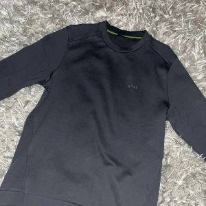 Svart tröja från Boss - Snygg svart tröja från Boss i storlek S. Tröjan har en stilren design med diskret logga på bröstet och rund halsringning. Perfekt för en avslappnad men ändå elegant look.