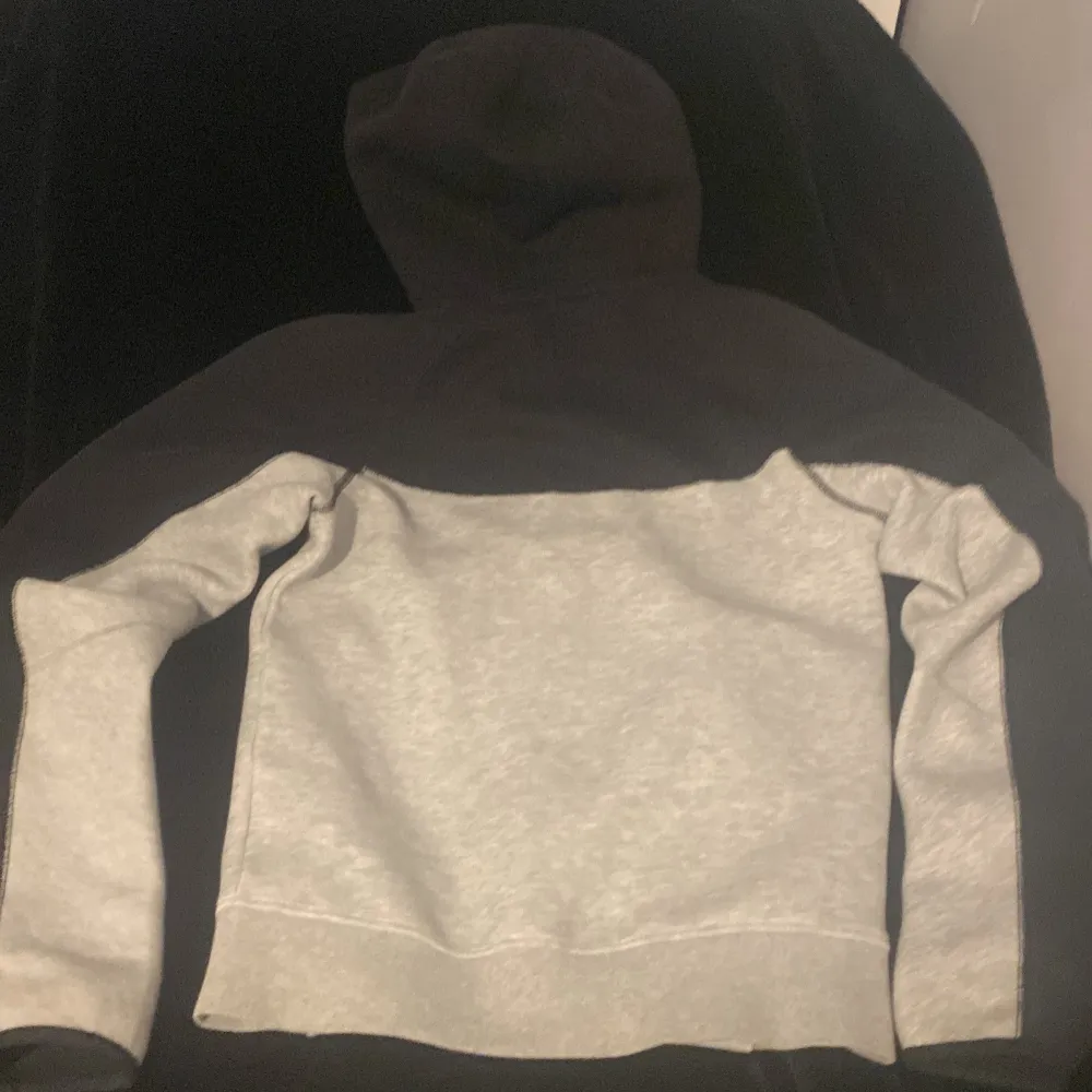 Säljer en grå och svart Nike tech fleece. Tröjan har en klassisk Nike-logga på bröstet och är perfekt för en sportig look. Huvan ger extra komfort och stil. . Hupparit & Collegepaidat.