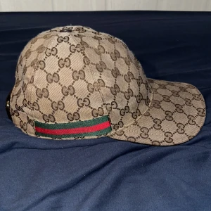 Beige Gucci keps  - Snygg beige äkta Gucci keps med klassiskt monogrammönster och justerbart spänne bak. Säljer då jag inte har någon användning. Pris är inte fast!!! Byten går bra.