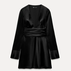 Svart satin klänning från Zara - Elegant svart klänning i satin från Zara med v-ringad design och långa ärmar. Klänningen har en markerad midja och en kort längd som ger en stilren look. Prislappen kvar, aldrig använd💕