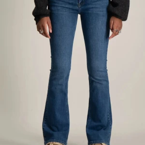 Blå bootcut jeans - Snygga blå bootcut jeans med klassisk femficksdesign. Perfekta för en avslappnad stil med en touch av retro. Passar bra till både sneakers och klackar.