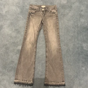 Grå bootcut jeans från Gina Tricot - Snygga grå bootcut jeans från Gina Tricot. De har en klassisk femficksdesign och en knappgylf. Perfekta för en avslappnad stil. Kanske bara använts 3-4 gånger eftersom det var försmå när jag köpte dem. 