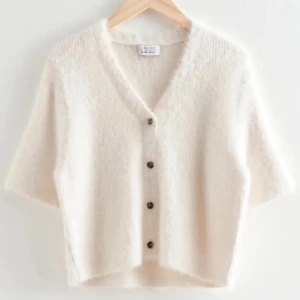 Vit kofta med knappar - Mysig vit kofta med knappar framtill. Den har en v-ringad design och trekvartsärmar, perfekt för en avslappnad stil. Koftan är tillverkad i ett mjukt material som ger en skön känsla. Lånade bilder men skriv för egna 🥰🥰