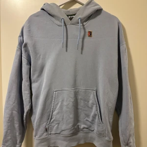 Ljusblå hoodie från Nike - Säljer en stilren ljusblå hoodie från Nike med en broderad logga på bröstet. Tröjan är från Nikes Bob marly hyllning där av färgerna är Nike loggan. Har en loose fit. Bra skick. För referens är jag 183cm 