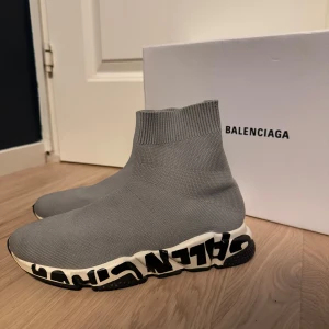 Grå sneakers  - Snygga grå sneakers från Balenciaqa med en stickad överdel och en unik sula med logotypdetaljer. Perfekta för en trendig look.                                                                       Kartong medföljs nt.