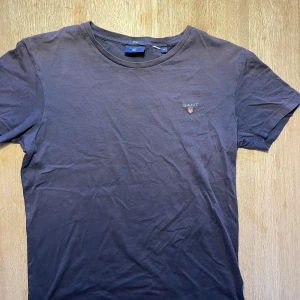 Mörkblå t-shirt från GANT - Säljer en snygg mörkblå t-shirt från GANT i storlek M. Den är i bomull och har en normal passform. T-shirten är kortärmad och har en liten GANT-logga broderad på bröstet. Perfekt för både vardag och fest!