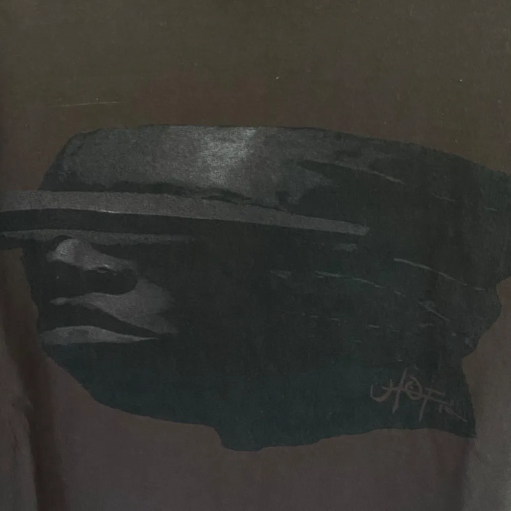 Säljer en brun t-shirt från Travis Scott med ett coolt tryck av ett ansikte i mörkare nyans på framsidan. T-shirten är i 100% bomull och har en normal passform. Perfekt för vardagsbruk eller för att ge din outfit en unik touch! . T-shirts.