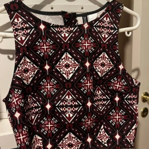 Mönstrad klänning från Shein - Säljer en oanvänd topp från H&M med ett unikt geometriskt mönster, vinrött, svart och vitt. Toppen är ärmlös och perfekt för både vardag och fest. Den har en dragkedja i ryggen för enkel påklädning. Passar perfekt för höst och vinter.