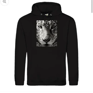 Svart hoodie med leopardmotiv - Säljer en svart hoodie med ett stort leopardmotiv på framsidan. Den är superbekväm och perfekt för både chill och vardagsäventyr. Hoodien har en klassisk passform med långa ärmar och en praktisk ficka framtill. Perfekt för dig som vill ha en cool och djärv stil! 🐆