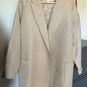 Beige kappa från Carin Wester - Säljer en superfin beige kappa från Carin Wester i storlek 36. Den har en klassisk design med långa ärmar och knappar framtill. Perfekt för höst och vår, och den ger en stilren look till vilken outfit som helst. Kappan är i bra skick och passar både till vardags och lite finare tillfällen.