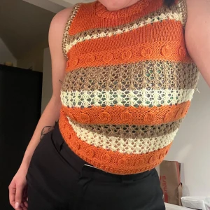 Randig stickad ärmlös topp - Säljer en superfin stickad topp i härliga höstfärger! Den är randig i orange, beige och brun med ett snyggt mönster. Perfekt för både vardag och fest. Toppen är ärmlös och har en tight passform som framhäver figuren. Passar perfekt till ett par höga byxor eller kjol. 🧡🤎den är handgjord (inte av mig, jag har köpt den) och är lite stram ut vid axlarna och kan nog vara stl M 