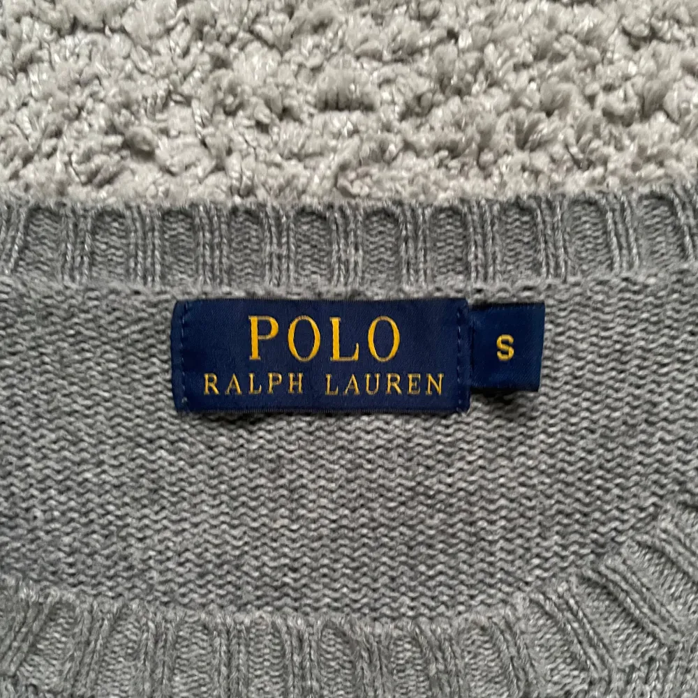 Säljer en stilren grå stickad tröja från Polo Ralph Lauren.  Den är i nyskick. Perfekt för höst och vinter. Passar både till vardags och lite finare tillfällen. Modellen är 178 cm, skriv vid minsta lilla 🍾 . Tröjor & Koftor.