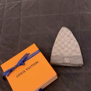 Snygg grå mössa från Louis Vuitton i ett klassiskt rutigt mönster. Perfekt för att hålla sig varm med stil under kyliga dagar. Kommer i originalförpackning, vilket gör den till en perfekt present eller lyxig uppgradering av din garderob.