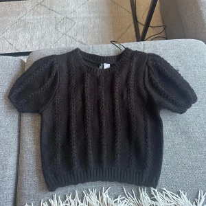 Mörkbrun stickad tröja från H&M - Säljer en superfin mörkbrun stickad tröja från H&M. Den har korta puffärmar och ett ribbat mönster som ger en snygg textur. Perfekt för höst och vinter, och den är i mycket bra skick. Passar perfekt till både jeans och kjol!