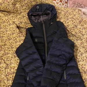Mörkblå pufferjacka från Uhip - Säljer en mörkblå pufferjacka från Uhip då jag köpte fel storlek men han inte lämna tillbaka den den. Är helt ny, lapparna är till och med kvar. Den är en bekväm och varm jacka som kommer göra dina stalldagar mycket roligare då du slipper frysa. Orginarie pris: 1675 kr mitt pris 1400kr, pris kan diskuteras 