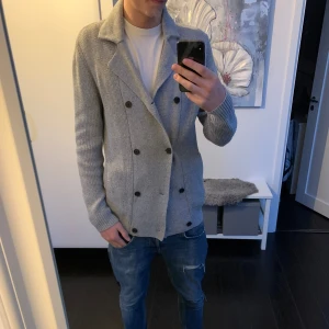 Grå stickad kavaj - Säljer en snygg grå stickad kavaj med dubbelknäppning. Perfekt för höst och vår, med långa ärmar och en stilren look. Den är i bra skick och passar både till vardags och lite finare tillfällen. Hör av er vid frågor, pris ej hugget i sten!! 🪨 