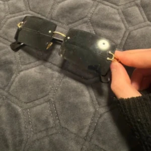 Svarta solglasögon med gulddetaljer - Snygga svarta solglasögon med gulddetaljer. De har en modern design med rektangulära linser och en stilren look. Perfekta för både vardag och fest!