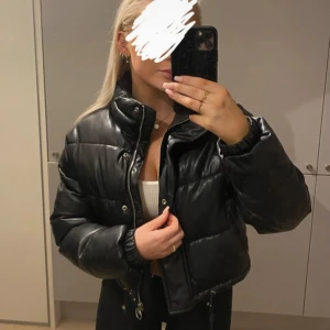 Svart pufferjacka - Säljer en riktigt snygg svart pufferjacka i mycket bra skick. Storlek XS ✨ Den är perfekt för höst och vinter! Jackan är i skinnimitation därav glansig i materialet. Har dragkedja framtill och även knappar. Öppna fickor på båda sidor. Den är som ny 🖤