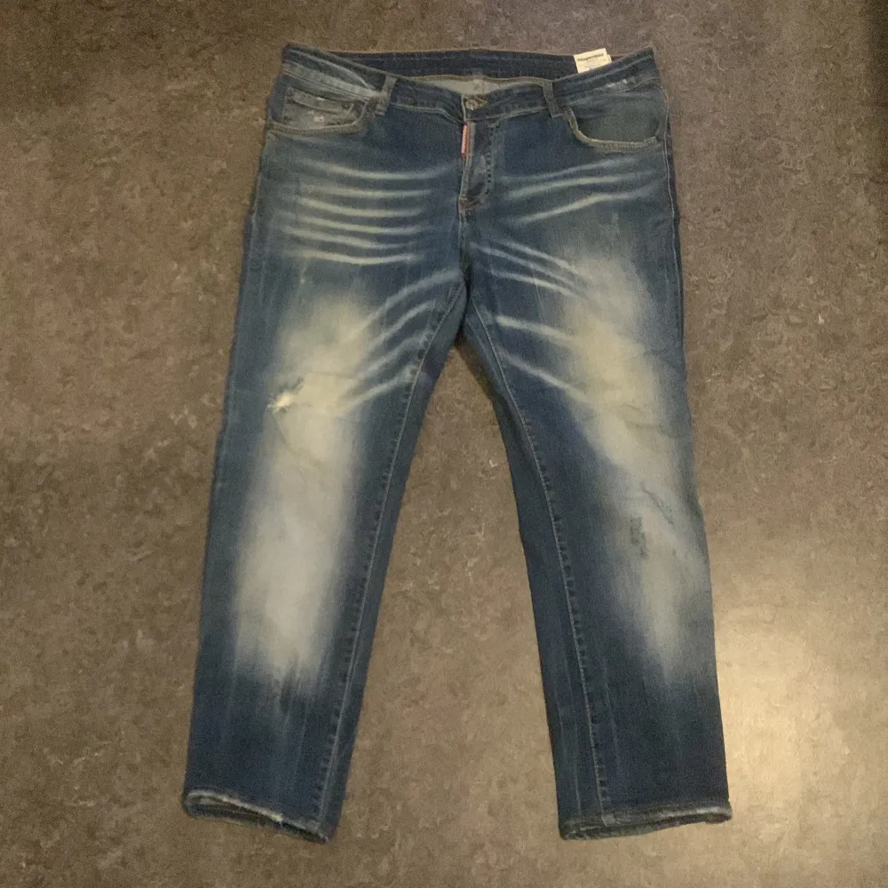 Säljer ett par snygga blå jeans från Dsquared2 i storlek 54. De har en cool slitningseffekt och är i slim fit. Perfekta för både vardag och fest! Tillverkade i Italien med hög kvalitet. Passar perfekt till en casual look eller när du vill klä upp dig lite extra.. Jeans & Byxor.