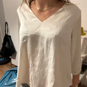 Vit satinblus - Säljer en stilren vit blus med v-ringning och trekvartsärmar. Perfekt för både vardag och fest💕