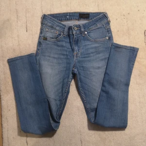 Blå jeans från Tiger of Sweden - Säljer ett par snygga blå jeans från Tiger of Sweden i bra skick. De har en klassisk femficksdesign och är tillverkade i slitstarkt denim. Perfekta för både vardag och fest! 🕺