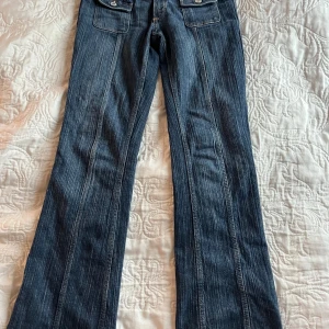 Blå bootcut jeans från H&M - Säljer ett par snygga blå bootcut jeans från H&M i storlek EUR 158. De har låg midja och justerbar midja för perfekt passform. Perfekta för en avslappnad stil med en touch av retro. Använda men i bra skick!