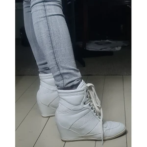 Sneakers med kilklack 39 - Bra skick, de är i tyg/plast inte läder, så ingen hög kvalité. Öljetterna har oxidering (sista bilden), går nog att tvätta bort. Lite små i storleken, jag brukar ha 37-38 och kan ha dem. Kan skicka mer bilder.