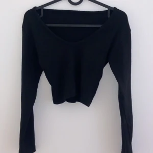 Svart långärmad tröja - Säljer en stilren svart tröja med lång ärm och v-ringad hals. Perfekt för både vardag och fest. Tröjan har en enkel design som gör den lätt att matcha med olika outfits. Passar bra till höst och vinter.