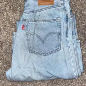 Ljusblå jeans från Levi's - Säljer ett par klassiska ljusblå Levi's jeans i bra skick i high loose. De har den ikoniska läderpatchen och den röda Levi's-taggen på bakfickan. Perfekta för en avslappnad vardagslook. Passar till allt. Högmidjade, vida och raka i modellen.