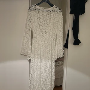 Vit spetsklänning - Vit (genomskinlig) spetsklänning som används över ex. bikinis. Öppen i ryggen, går ner till fötterna på mig ungefär (jag är 170cm)