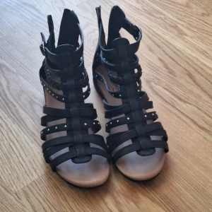 Svarta sandaler - Snygga svarta sandaler med coola nitar och remmar. Perfekta för en sommarfest eller en utekväll. Är u storlek 34.