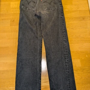 Svarta Levi's Ribcage Straight Ankle Jeans - Säljer ett par svarta Levi's Ribcage Straight Ankle jeans i storlek 27. De är i mycket bra skick och har en hög midja som ger en snygg siluett. Perfekta för både vardag och fest! 🖤
