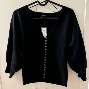 Svart kofta Lindex - Säljer en stilren svart kofta från Lindez i storlek S. Den har en v-ringad design med knappar hela vägen ner och långa ärmar. Perfekt för både vardag och fest! 🖤Köpt för 499kr, helt oanvänd! Pris kan diskuteras! 