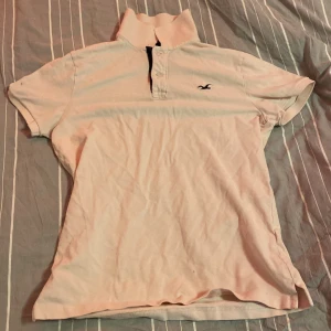 Vit pikétröja från Hollister - Säljer en vit pikétröja från Hollister i storlek S. Tröjan har korta ärmar och en klassisk krage med knappar. Den är i bra skick och perfekt för en avslappnad stil. Passar både till vardags och lite finare tillfällen.